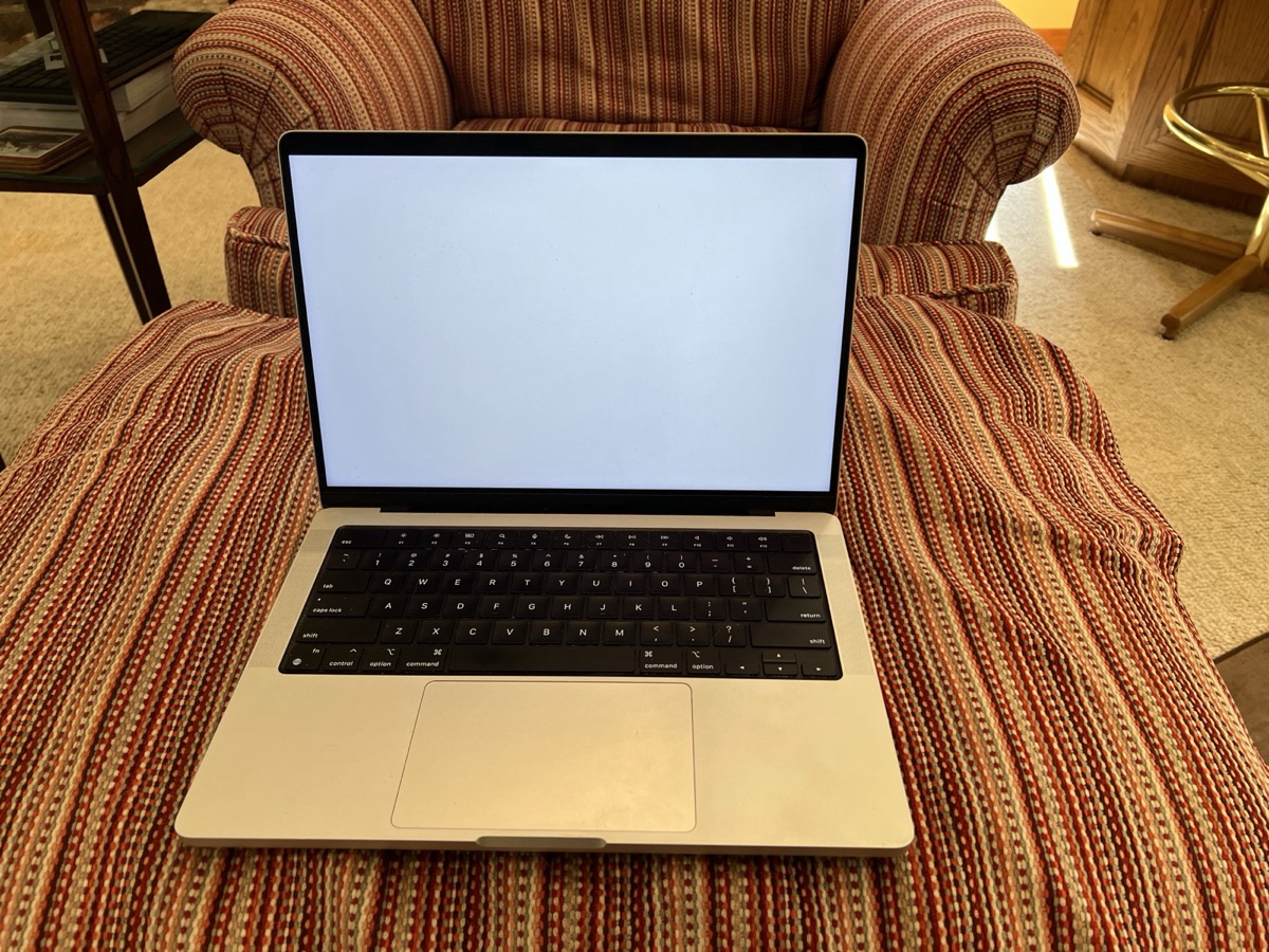 A silver 14-inch MacBook Pro open on a desk - the current design that Bloomberg's Mark Gurman reports Apple will overhaul into its first OLED, touchscreen Mac