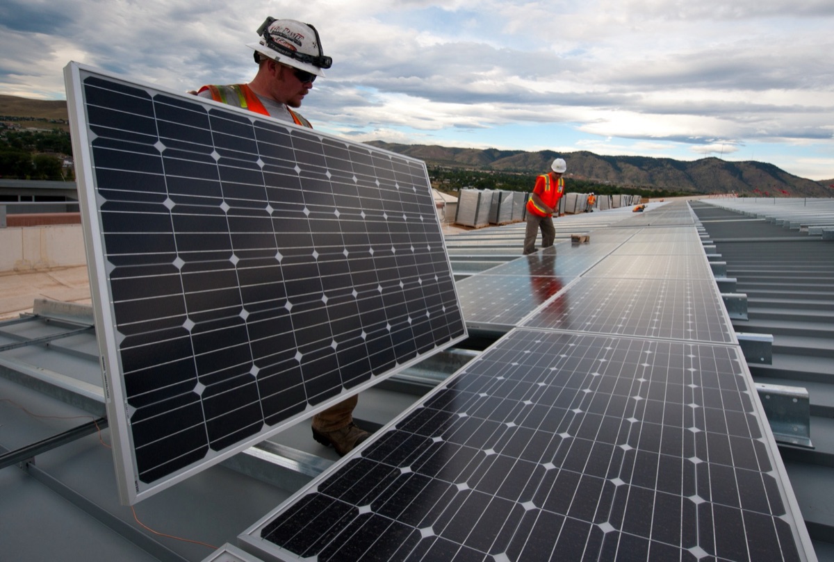 Rooftop solar photovoltaic panels under a clear sky, illustrating an artificial-photosynthesis system that uses sunlight to turn water and CO2 into liquid formic acid fuel