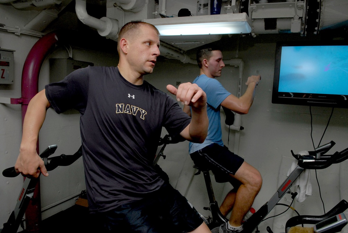 A person pedaling hard on a stationary bike in an indoor cycling (spin) class, illustrating the kind of high-intensity interval cardio (HIIT) the study used; a representative gym image, not the study's older participants.