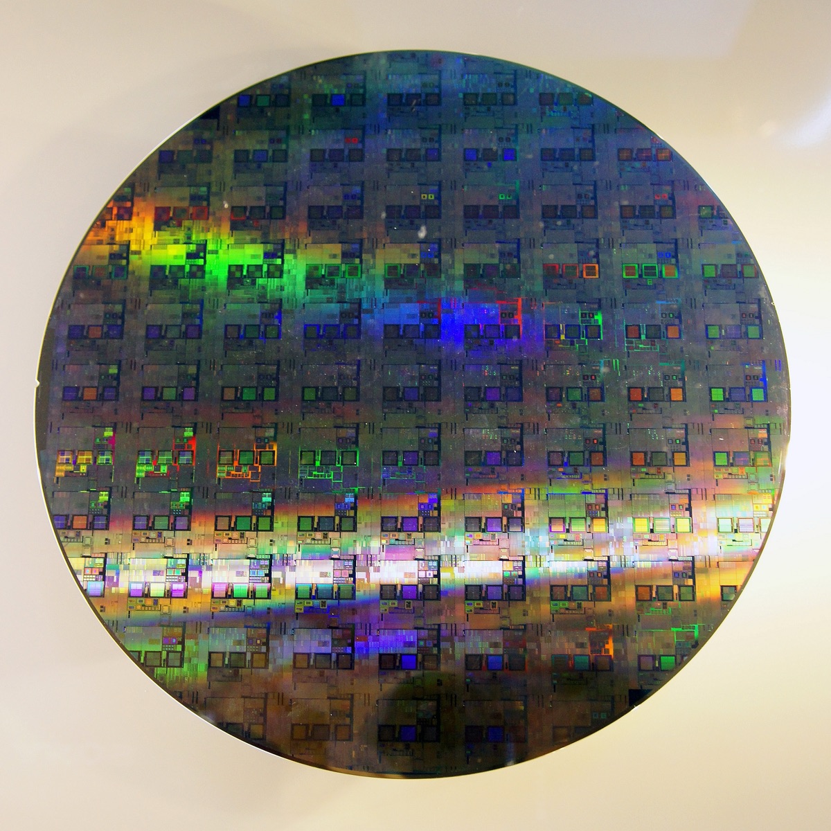 A 300mm (12-inch) silicon wafer with iridescent dies - the medium on which advanced semiconductors are fabricated - representing IBM's June 2026 sub-1-nanometer NanoStack chip breakthrough (representative image, not IBM's actual chip).