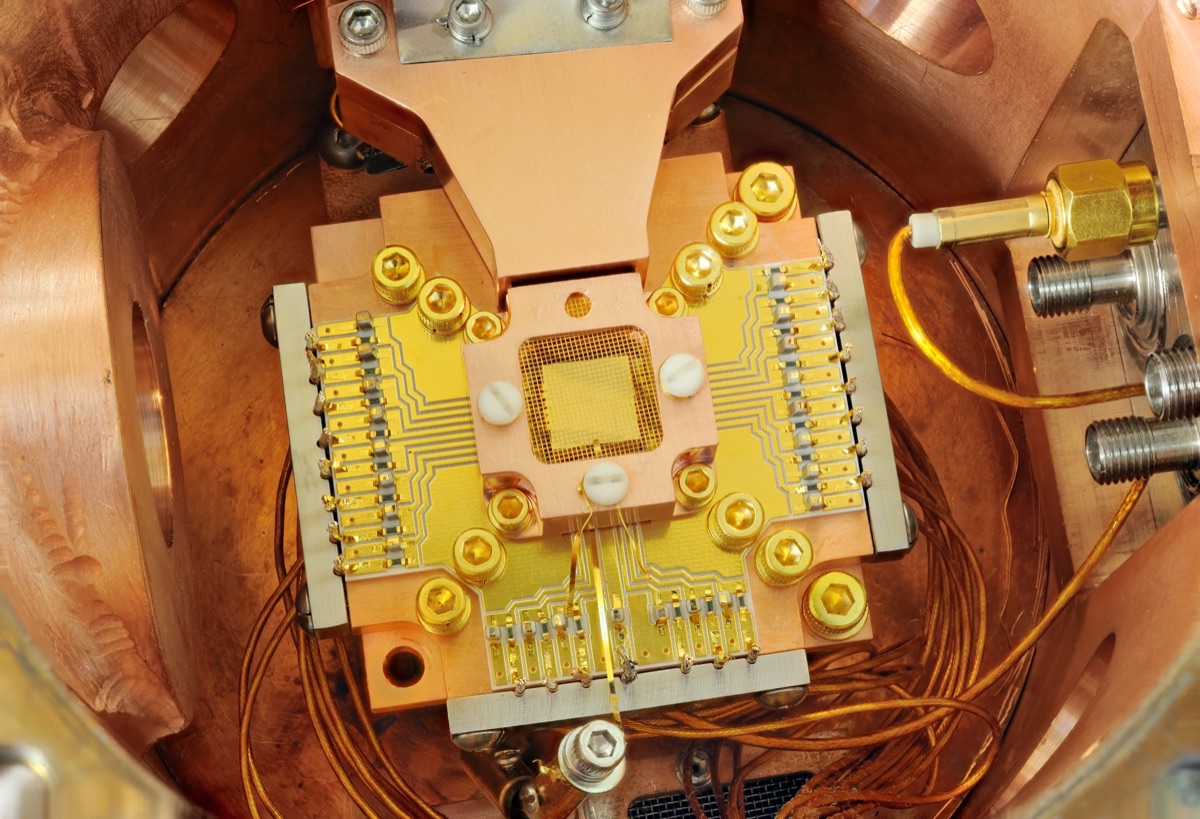 A surface-electrode ion-trap chip from NIST that uses tiny electrodes to hold individual charged atoms as qubits - the same trapped-ion approach behind Quantinuum's 98-qubit Helios quantum computer.